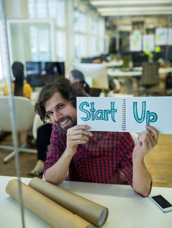 Male graphic designer holding spiral notepad with a text in office